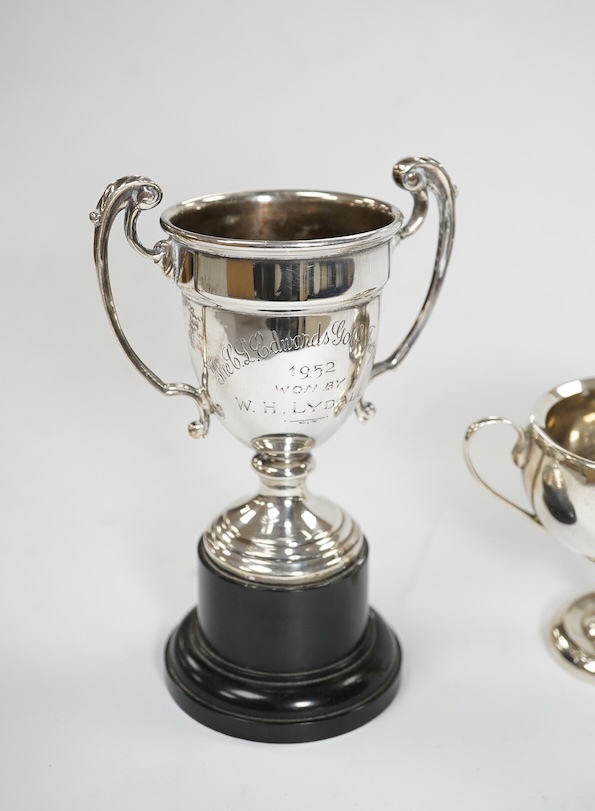 A pair of Edwardian silver dwarf candlesticks, of tapering design, C.S Green & Co, Birmingham, 1908, 13.2cm, together with four small silver trophy cups, a silver napkin ring and a plated trophy cup. Condition - poor to